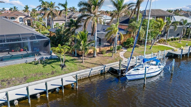 dock area featuring glass enclosure, a water view, and a yard