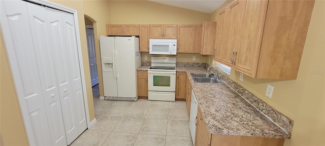 kitchen with light brown cabinets, lofted ceiling, white appliances, sink, and light tile patterned floors