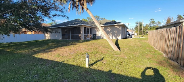 back of house featuring a lawn and a sunroom