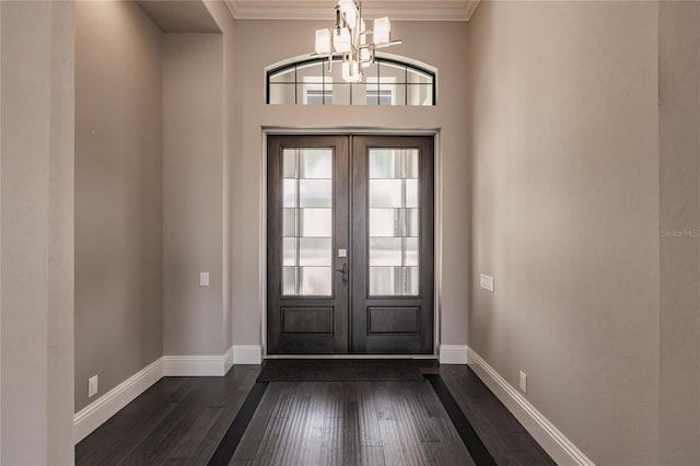 foyer featuring french doors, dark hardwood / wood-style flooring, crown molding, and a notable chandelier