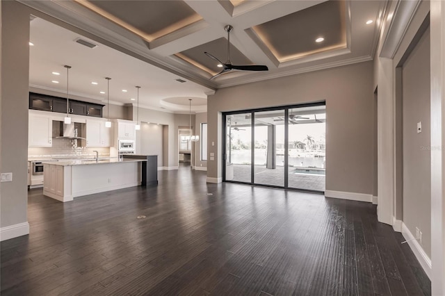 unfurnished living room featuring ceiling fan, coffered ceiling, beamed ceiling, dark hardwood / wood-style floors, and ornamental molding