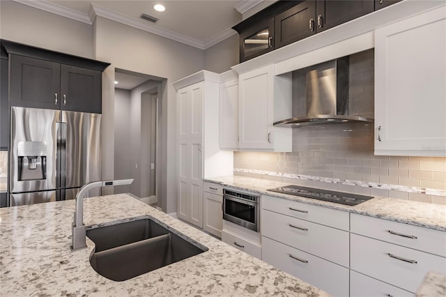 kitchen with decorative backsplash, wall chimney exhaust hood, stainless steel appliances, sink, and white cabinets