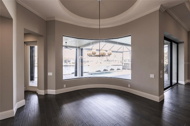 unfurnished dining area featuring a tray ceiling, a wealth of natural light, dark wood-type flooring, and ornamental molding