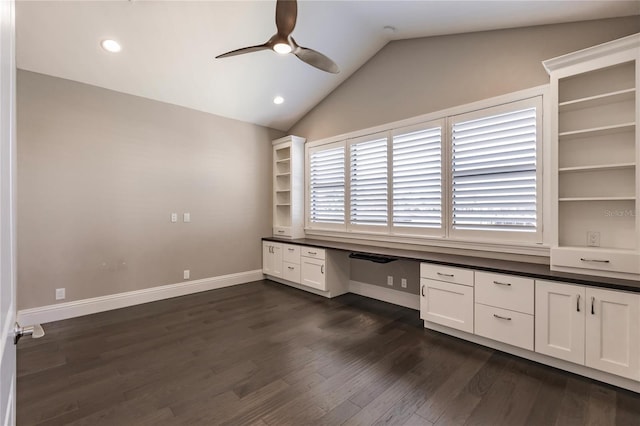 unfurnished office with ceiling fan, dark hardwood / wood-style flooring, built in desk, and vaulted ceiling