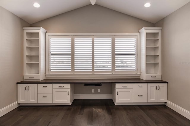 unfurnished office featuring dark hardwood / wood-style flooring, built in desk, a wealth of natural light, and vaulted ceiling