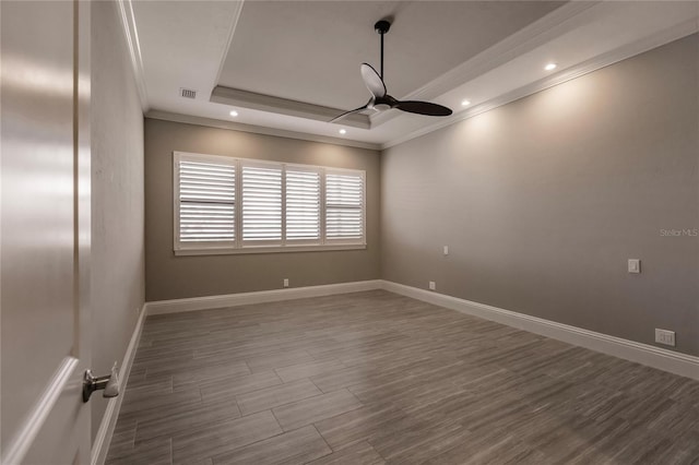 empty room featuring hardwood / wood-style flooring, ceiling fan, a raised ceiling, and crown molding