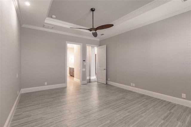 spare room featuring light wood-type flooring, a raised ceiling, ceiling fan, and crown molding