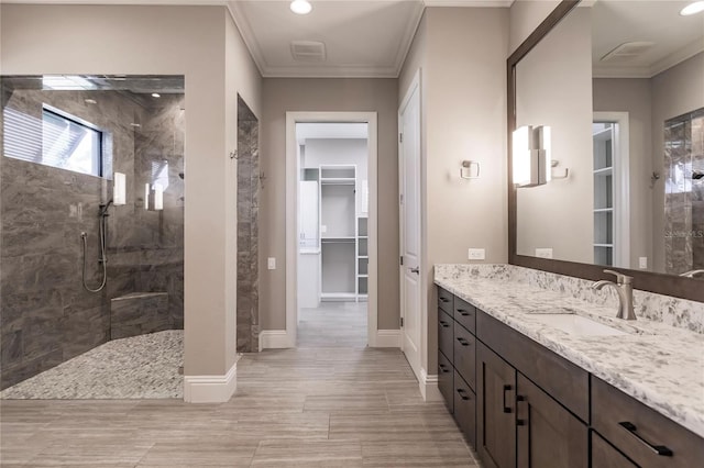 bathroom featuring vanity, ornamental molding, and tiled shower