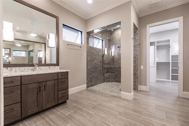 bathroom featuring a tile shower, vanity, ceiling fan, and ornamental molding