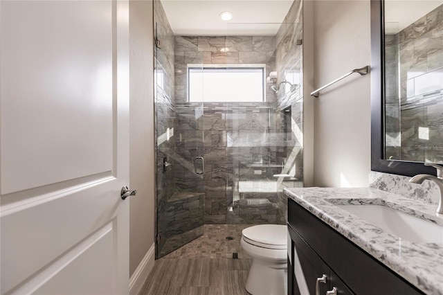 bathroom with vanity, toilet, and a shower with door