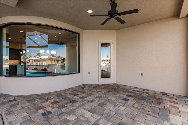 view of patio with ceiling fan and a water view