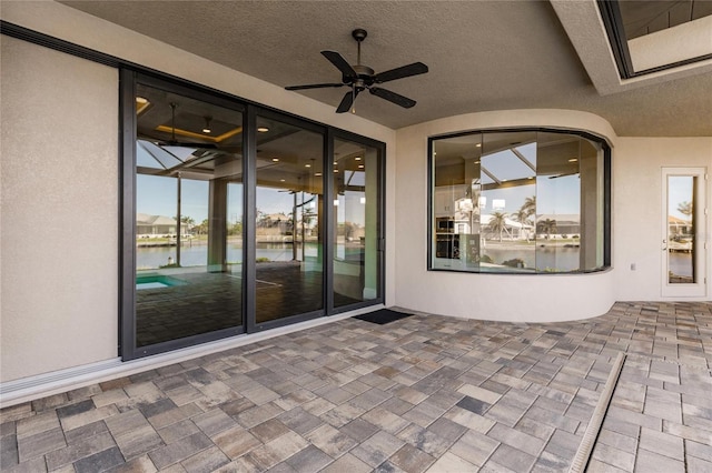 view of patio with ceiling fan and a water view