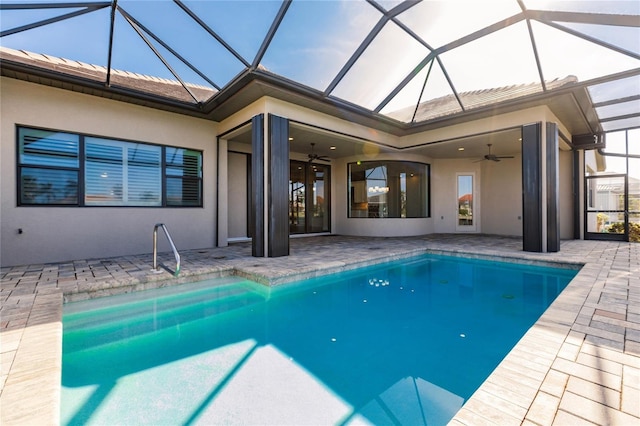 view of swimming pool with ceiling fan, a patio, and glass enclosure