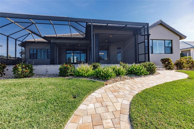 rear view of property featuring ceiling fan, a lanai, and a lawn