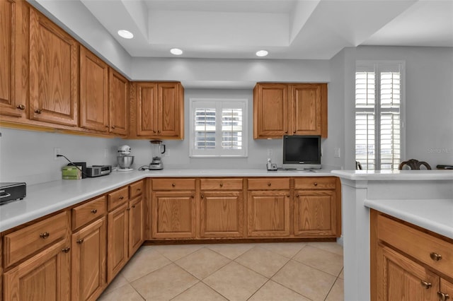 kitchen with a raised ceiling, plenty of natural light, and light tile patterned floors