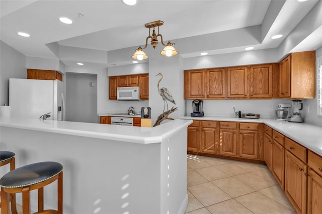 kitchen with hanging light fixtures, an inviting chandelier, white appliances, a breakfast bar, and light tile patterned floors