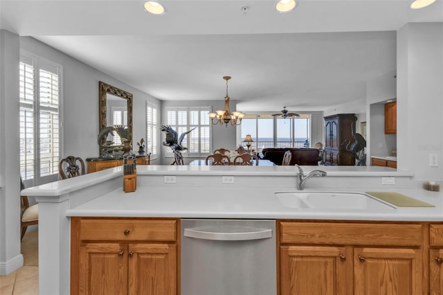 kitchen with dishwasher, sink, kitchen peninsula, light tile patterned floors, and ceiling fan with notable chandelier