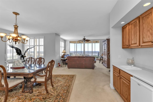 carpeted dining area featuring plenty of natural light and ceiling fan with notable chandelier