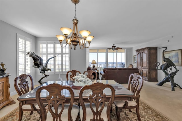 dining area with ceiling fan with notable chandelier and light colored carpet