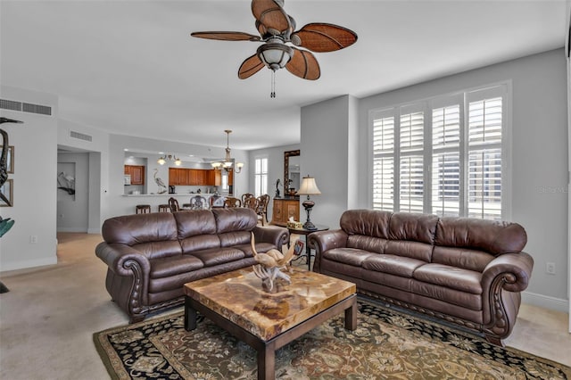 carpeted living room featuring ceiling fan with notable chandelier