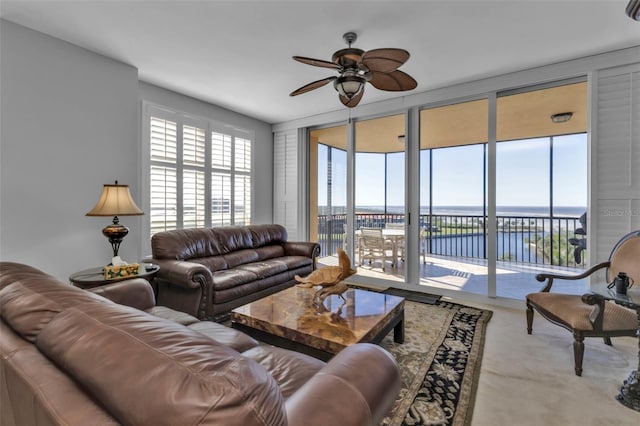 carpeted living room with ceiling fan and a water view