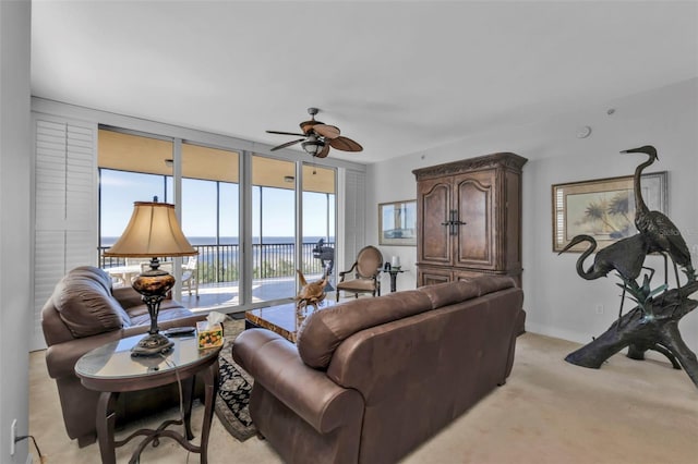 carpeted living room with floor to ceiling windows, a water view, and ceiling fan