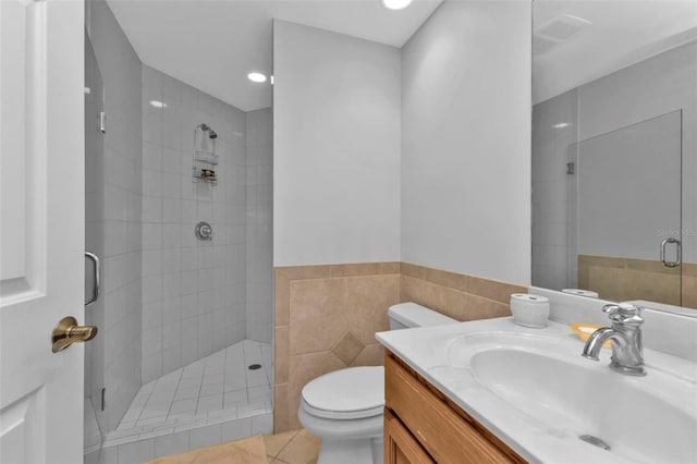 bathroom featuring tile patterned floors, walk in shower, vanity, tile walls, and toilet