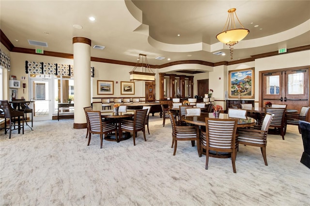 dining area featuring light carpet, a tray ceiling, decorative columns, and ornamental molding