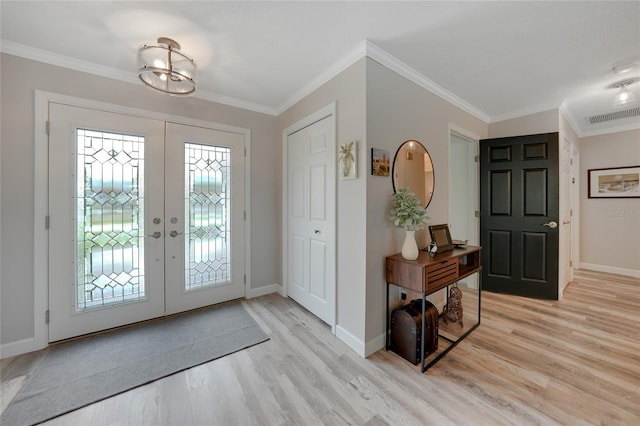 foyer with crown molding, french doors, an inviting chandelier, and light wood-type flooring