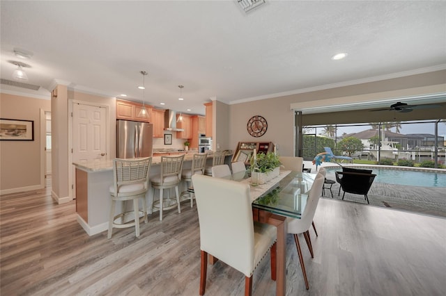 dining room with ceiling fan, light wood-type flooring, and ornamental molding