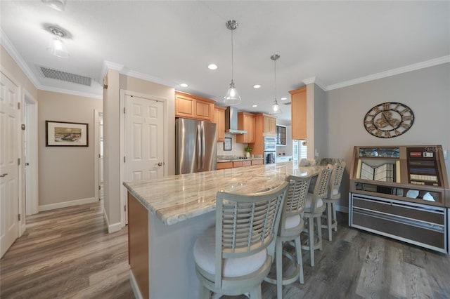 kitchen with a kitchen breakfast bar, crown molding, dark hardwood / wood-style floors, appliances with stainless steel finishes, and kitchen peninsula