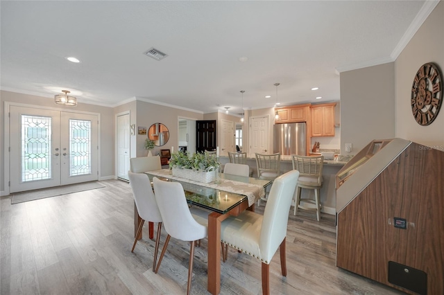 dining area featuring french doors, light hardwood / wood-style flooring, and crown molding