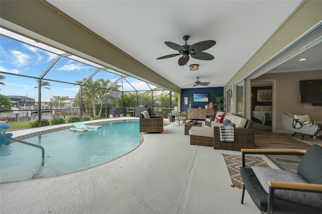 view of pool with glass enclosure, ceiling fan, a patio area, and an outdoor hangout area