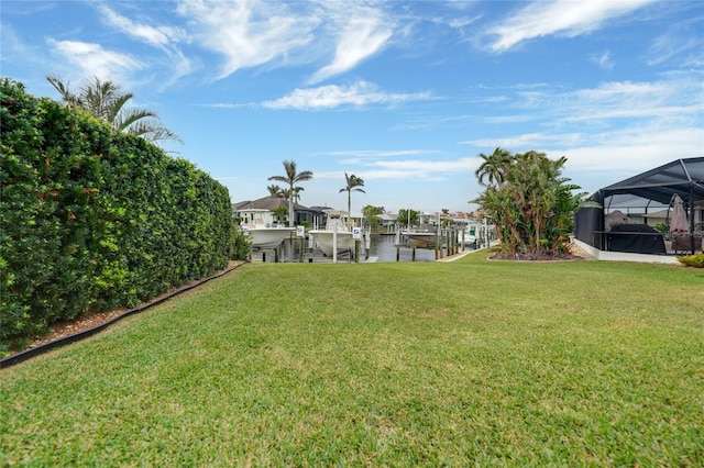 view of yard with a boat dock, a water view, and glass enclosure