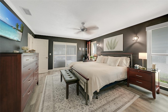 bedroom featuring ceiling fan, ornamental molding, and light wood-type flooring