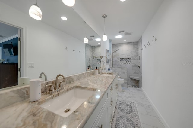 bathroom with a tile shower, vanity, and toilet