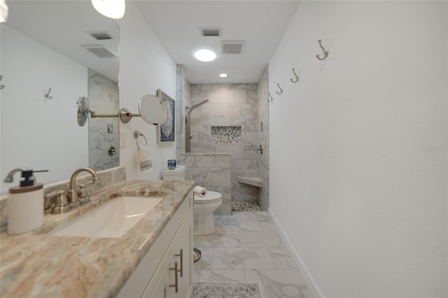 bathroom with toilet, vanity, and tiled shower