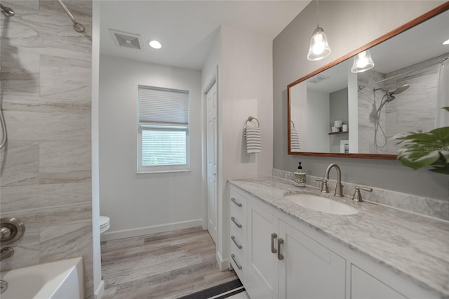 full bathroom with hardwood / wood-style floors, vanity, toilet, and tiled shower / bath combo