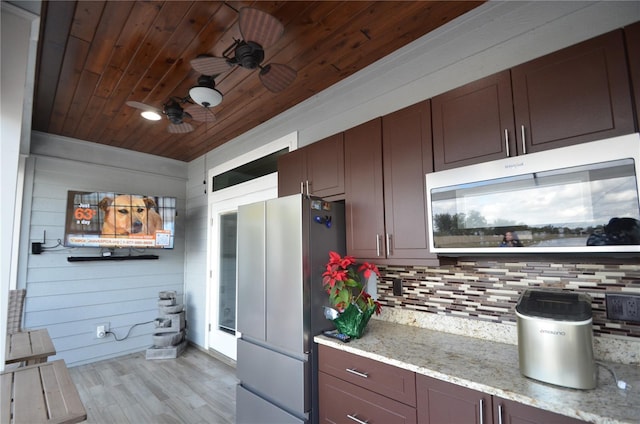 kitchen featuring wood walls, light hardwood / wood-style floors, stainless steel appliances, and tasteful backsplash