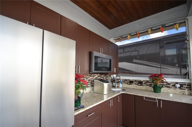 kitchen with tasteful backsplash, light stone countertops, sink, and appliances with stainless steel finishes