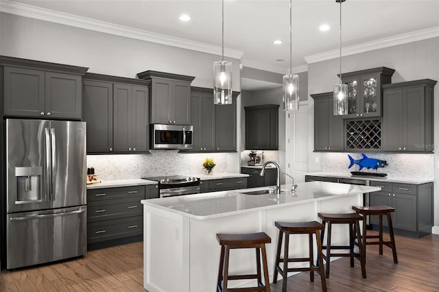 kitchen with dark wood-type flooring, sink, an island with sink, appliances with stainless steel finishes, and a breakfast bar area