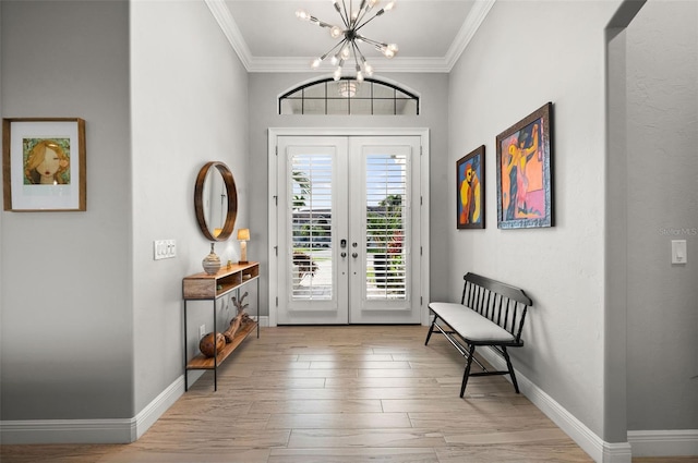 entryway featuring french doors, an inviting chandelier, ornamental molding, and light wood-type flooring