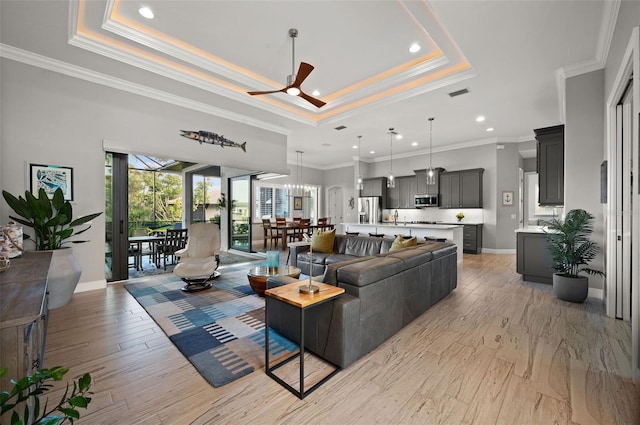 living room featuring a raised ceiling, crown molding, ceiling fan, and light hardwood / wood-style floors