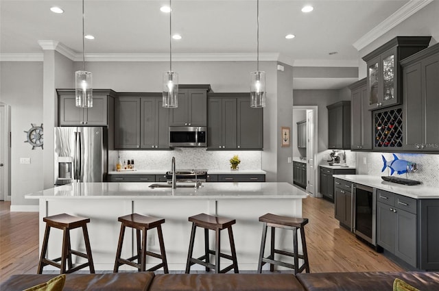 kitchen featuring a large island, sink, hanging light fixtures, light hardwood / wood-style flooring, and appliances with stainless steel finishes