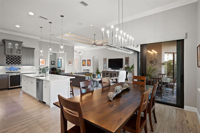 dining room featuring ornamental molding, sink, beverage cooler, and light wood-type flooring