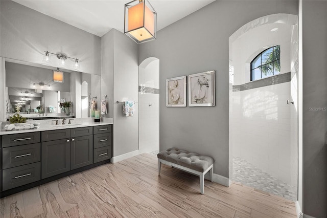 bathroom featuring vanity, wood-type flooring, and tiled shower