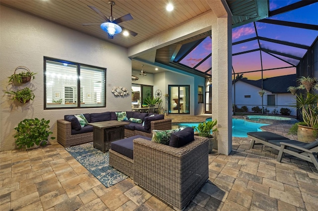 patio terrace at dusk featuring outdoor lounge area, ceiling fan, and a lanai