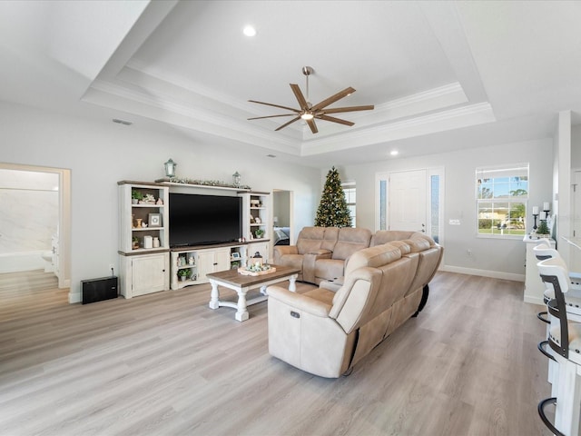 living room featuring a tray ceiling, ceiling fan, crown molding, and light hardwood / wood-style floors