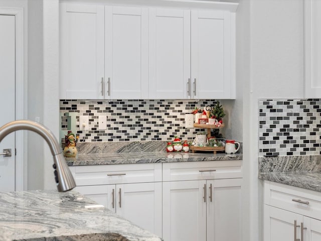 kitchen with white cabinets, decorative backsplash, and light stone counters