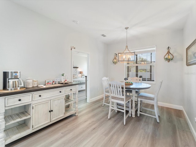 dining area with light hardwood / wood-style floors and an inviting chandelier